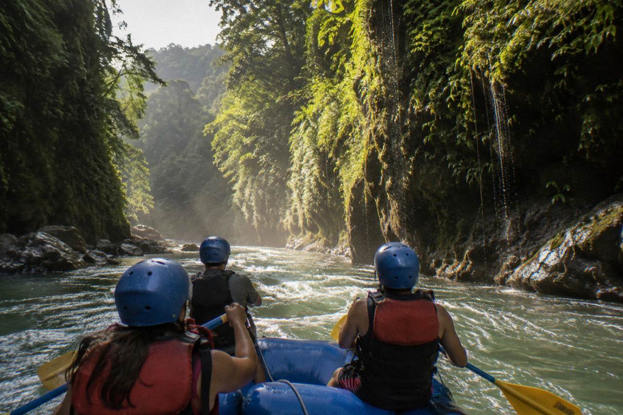 A raft passing through a narrow jungle gorge with steep green canyon walls