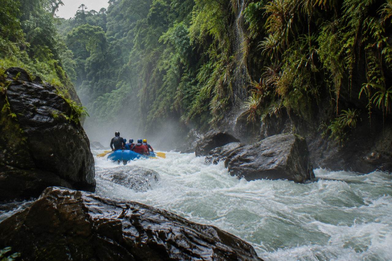 A raft cutting through a narrow jungle gorge with steep green canyon walls