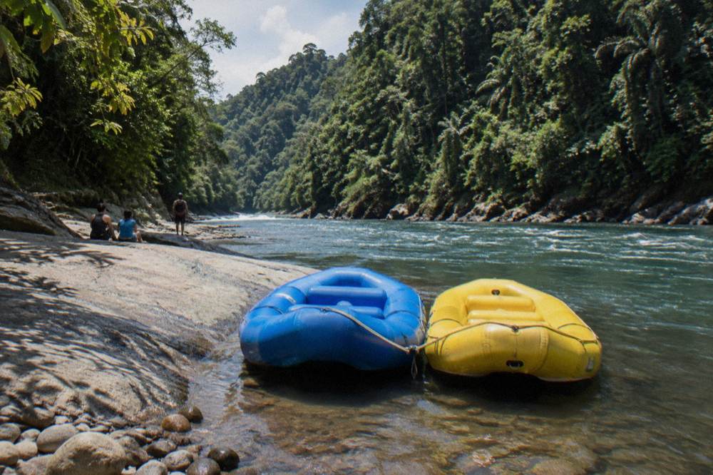 Two rafts tied together at a rocky riverbank lunch stop in the jungle