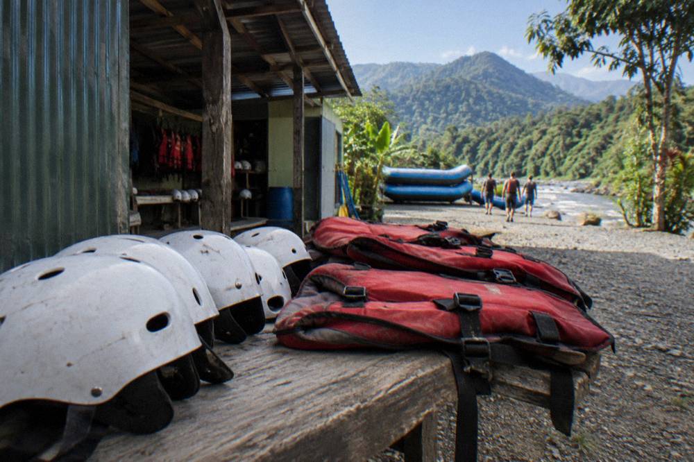 Life jackets and white water helmets laid out on a riverside bench before a trip