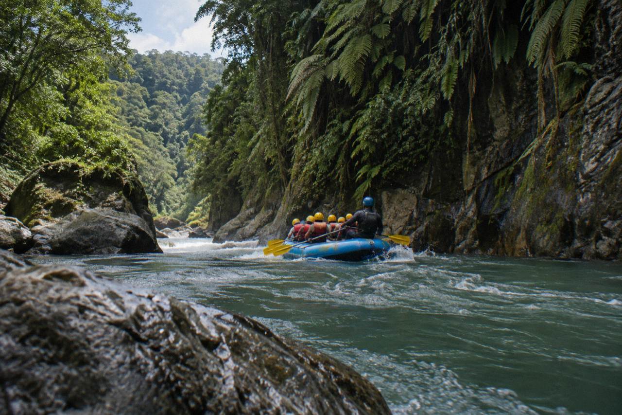 A raft cutting through a green jungle gorge on the Pacuare River