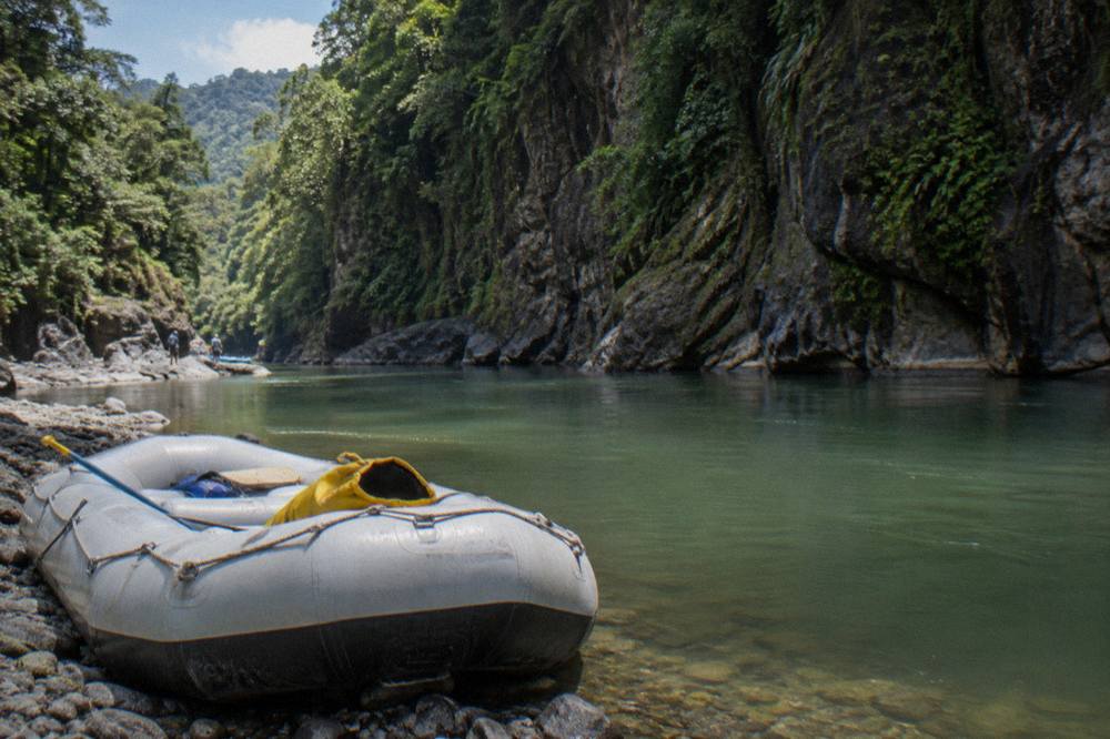 A calm pool between green canyon walls with a raft waiting at the shoreline
