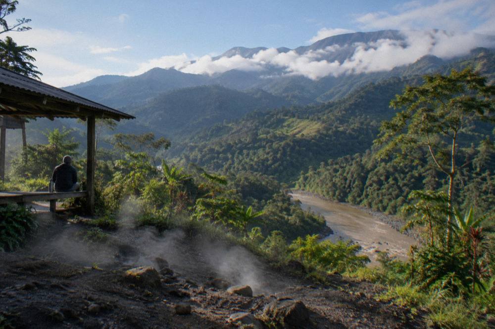 Dense green rainforest mountains with clouds resting on the ridgeline above a river valley