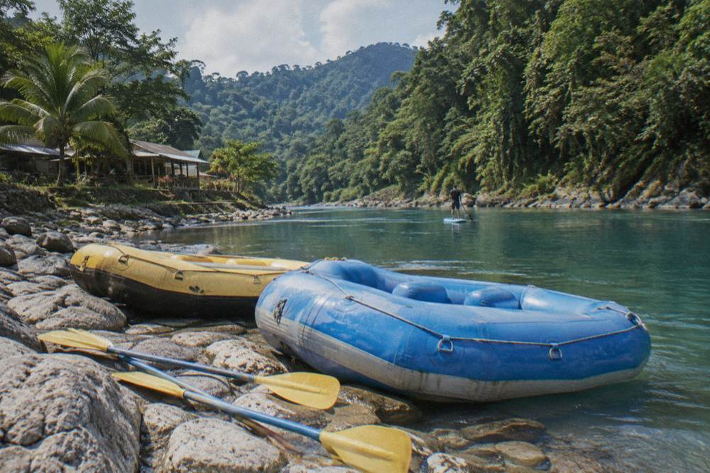 A calm turquoise pool between rapids with rafts pulled up on a rocky bank