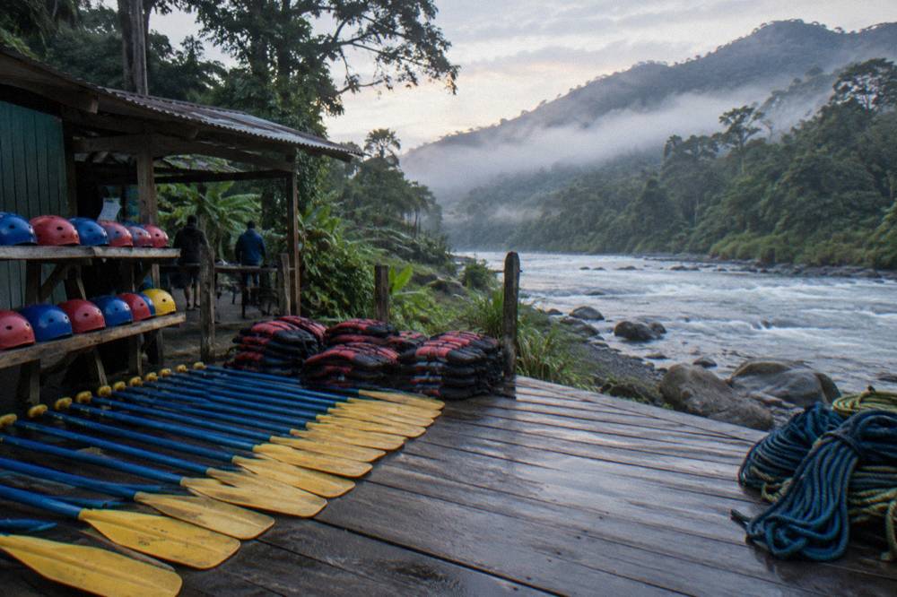 A paddles and helmets laid out on a riverbank platform before a rafting departure