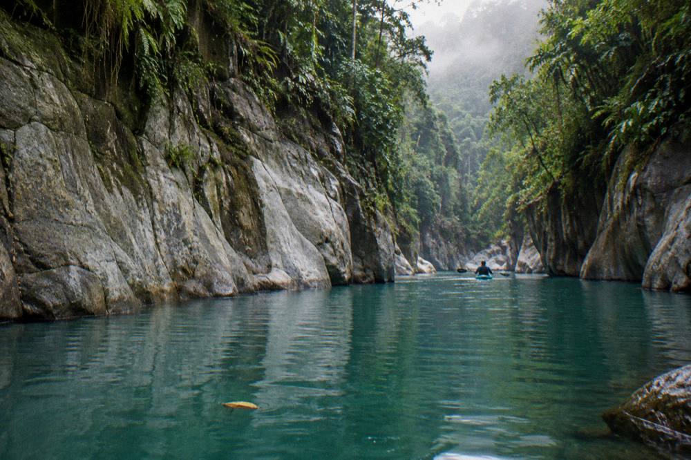 A calm turquoise pool in the Pacuare gorge with smooth rock walls rising above the water