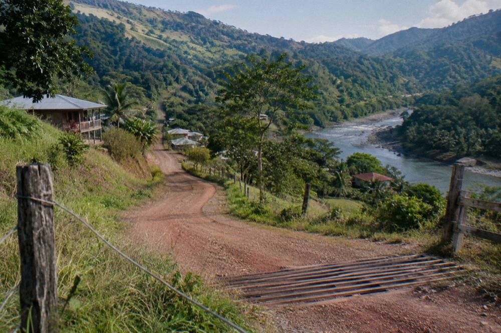 Winding rural road through green hills with volcano in the distance