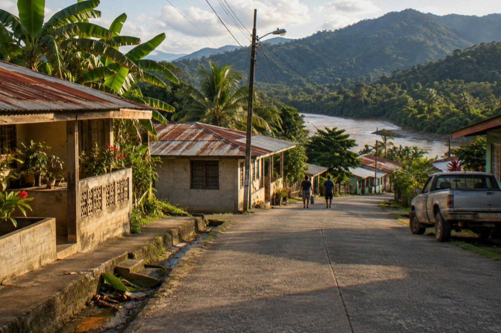 Small Costa Rican town street with green mountains rising behind the rooftops