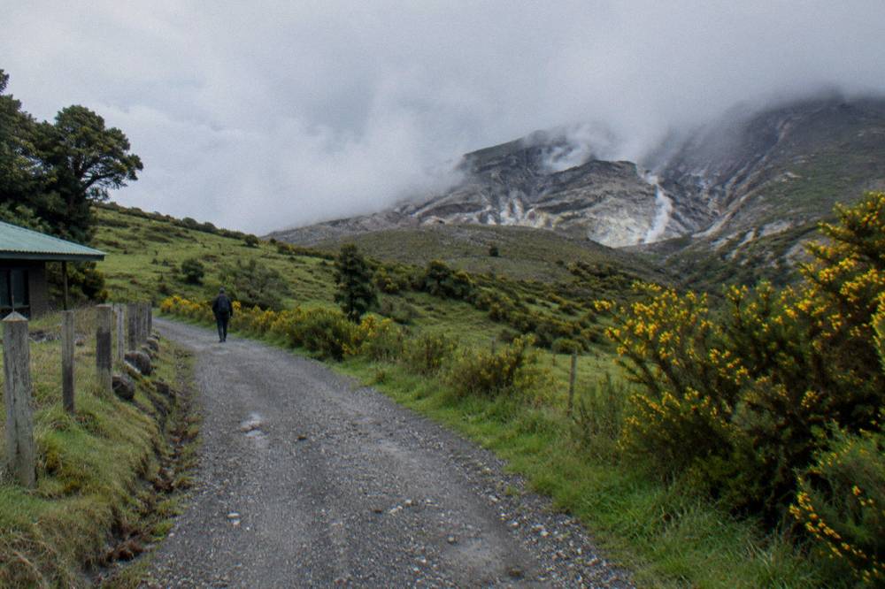 Quiet country road past green pastures with a small Costa Rican farming town in a valley