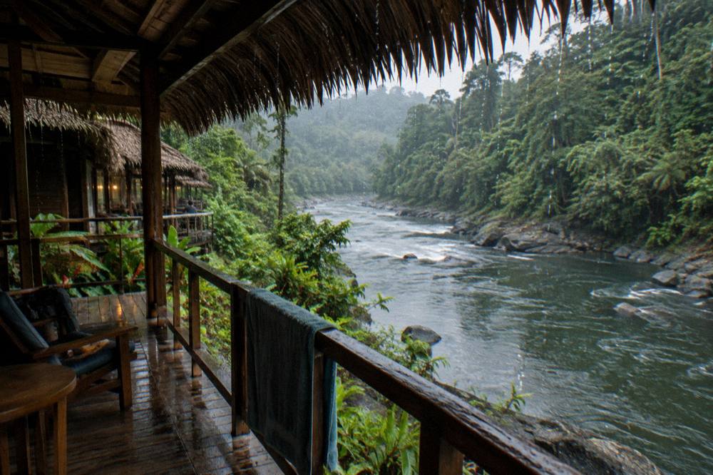 River lodge cabin with a wooden porch overlooking the Pacuare River inside the rainforest gorge
