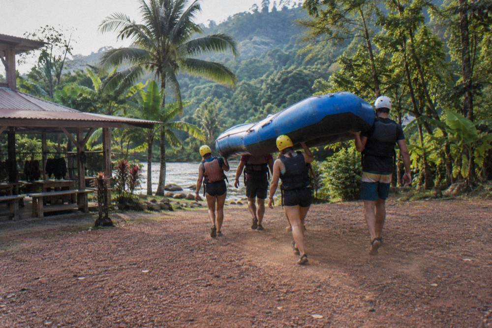 Small group of rafters carrying a raft toward the river through trees