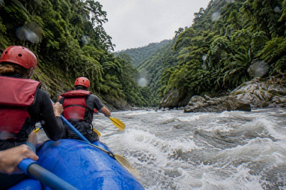 A raft paddling through a green jungle canyon with steep rock walls