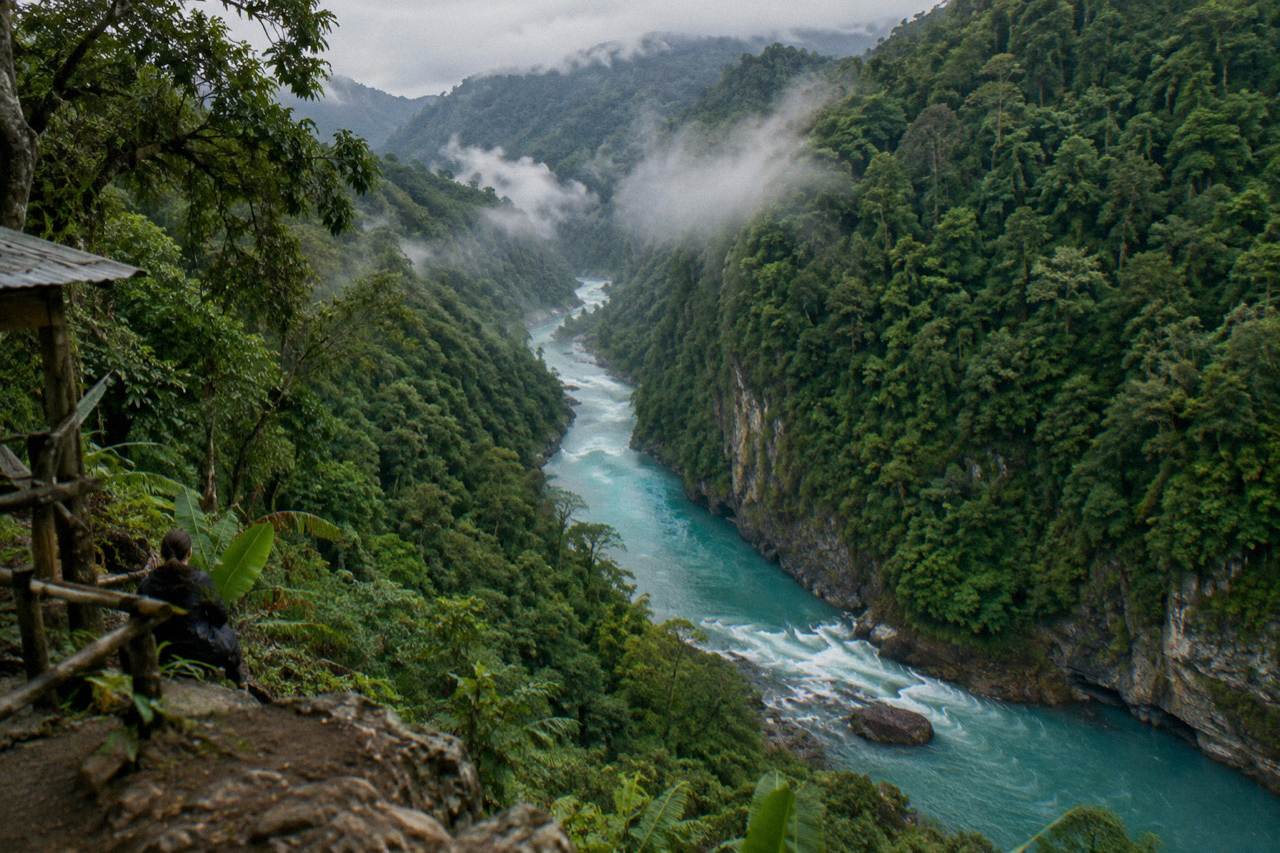 A rainforest gorge with a turquoise river winding between steep green walls