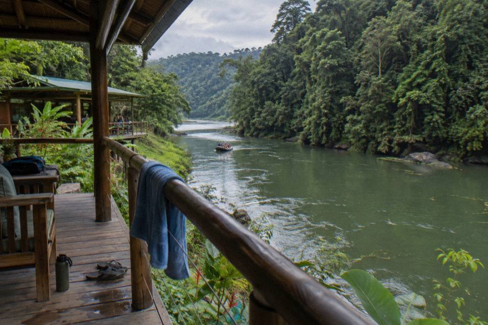 A raft floating on calm green water between two steep walls of rainforest.