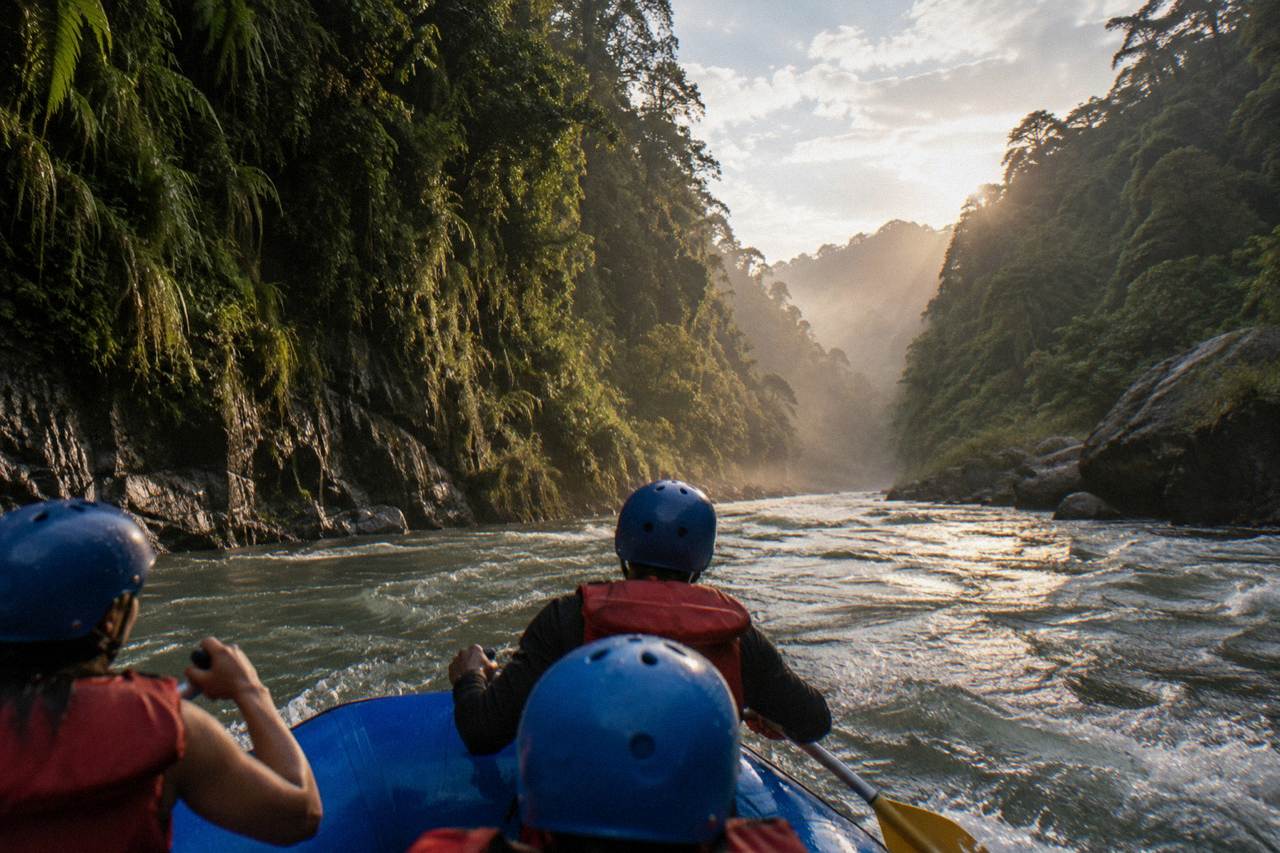 A raft cutting through a narrow jungle gorge with steep green canyon walls rising on both sides