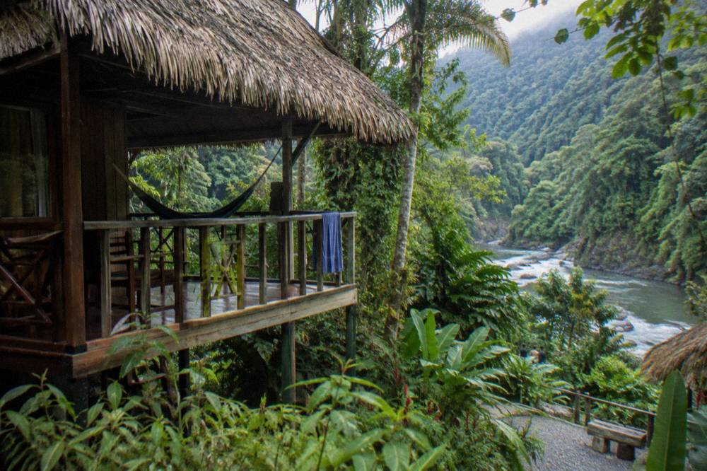Cabin bungalow with a covered porch above the dense green Pacuare river canyon