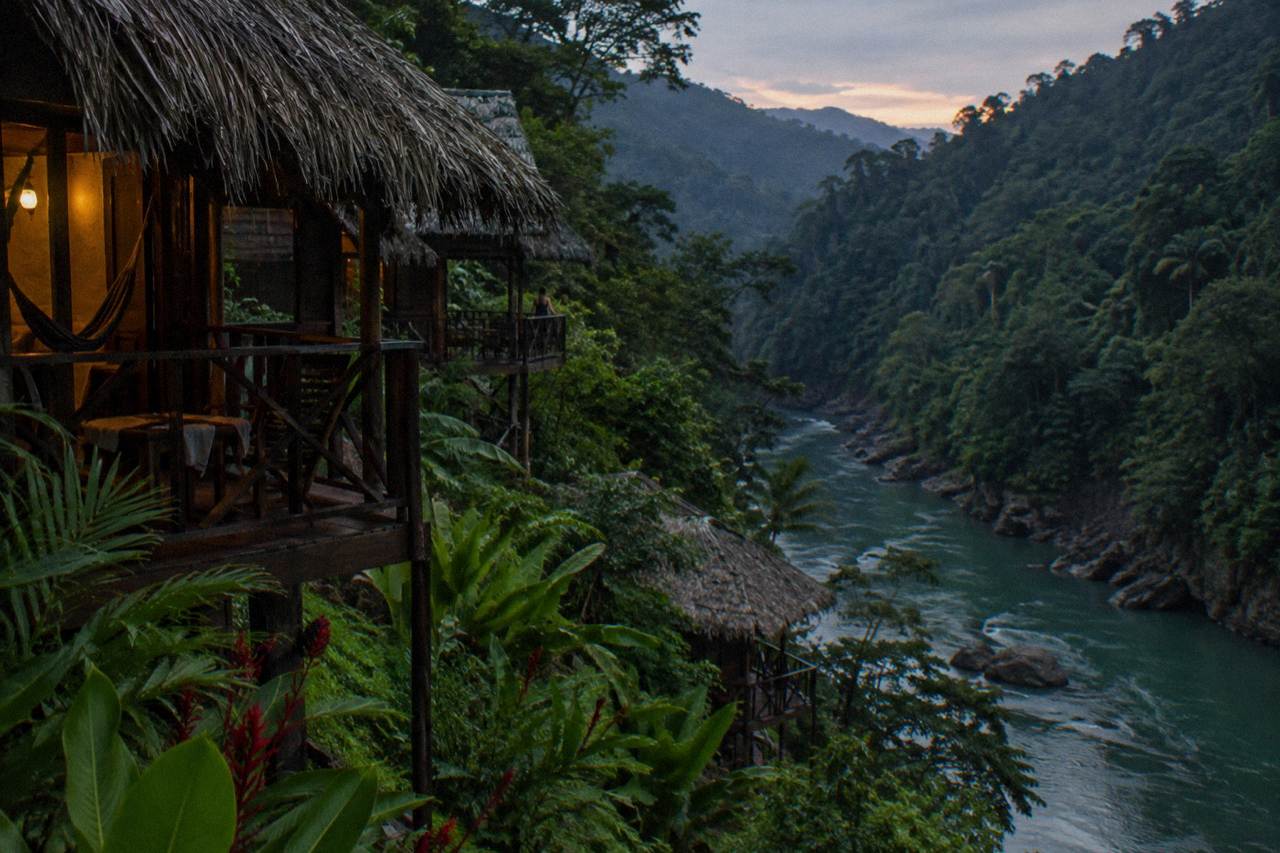Wooden river lodge balconies overlooking the green Pacuare gorge at dusk